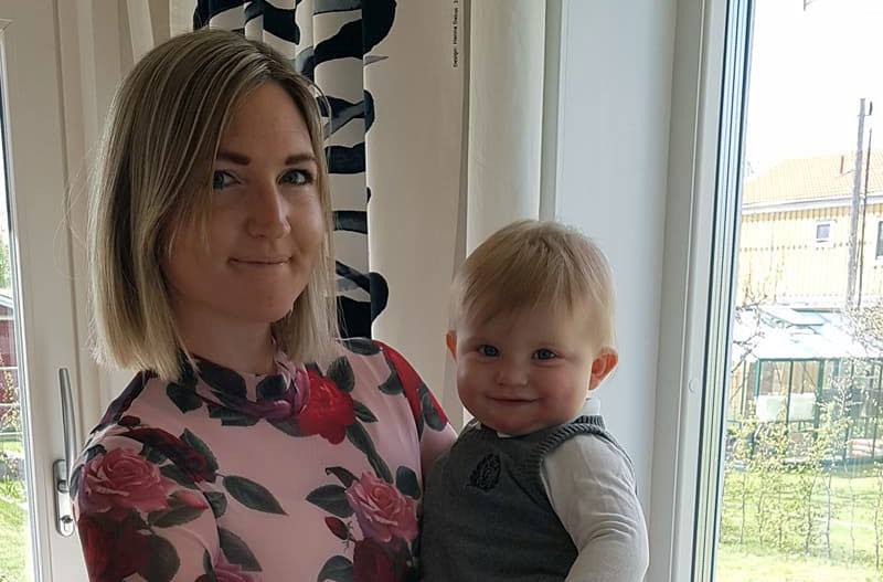Bild: Elvira, en blond tjej i blommig tröja, med ett litet barn i famnen.
