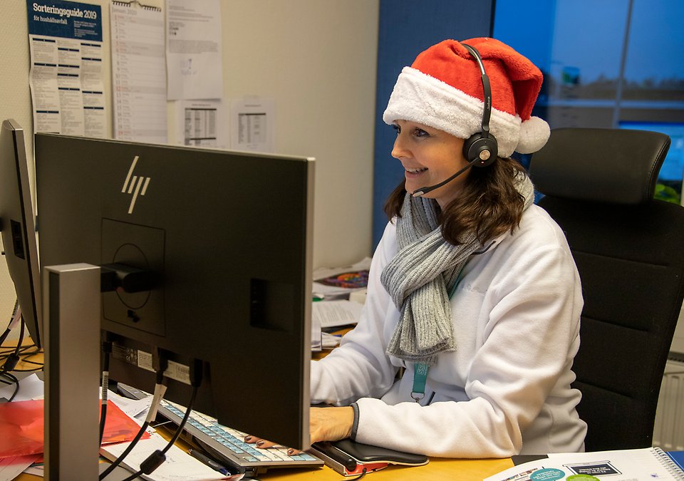 Kvinna med tomteluva sitter framför dator
